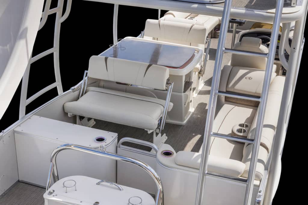 A view of the interior of a Catalina Cruise Funship showing padded bench seats, a table with cup holders, a steering area with a large dashboard, and polished metal handrails. The seating area has white upholstery, and there's a metal ladder leading to an upper level.