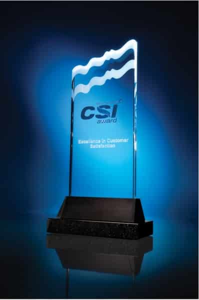A blue-tinted glass award with wavy edges, standing on a black base. The award has the words "CSI Award" and "Excellence in Customer Satisfaction" engraved on it. The background is illuminated with a blue gradient, highlighting the award's transparent design.