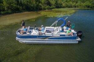 People fishing on an avalon pontoon boat, one person holding a net.