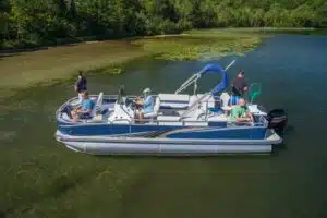 People fishing on an avalon pontoon boat, one person holding a net.