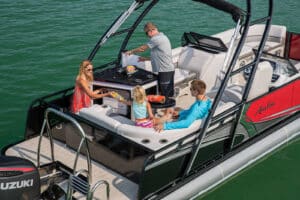 Family sharing bags of chips on a pontoon boat in a river.