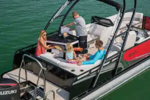 Family sharing bags of chips on a pontoon boat in a river.
