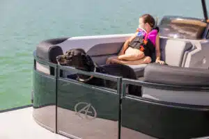 Girl in sitting in an Avalon Pontoon Boat next to a dog.