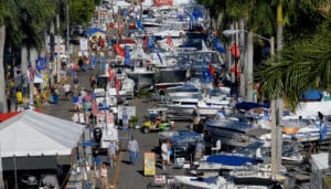 A view of the busy Fort Myers Boat Show. There are dozens of boats displayed on the street as pedestrians meander.