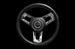 A black, three-spoke steering wheel with metallic accents and the word "AVALON" in the center, isolated on a black background.