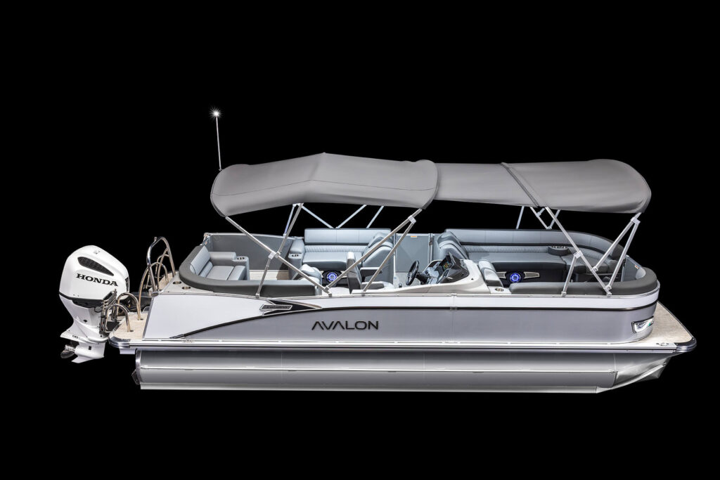 A side view of a silver pontoon boat with a Honda motor and an open deck covered by gray canopies. The boat has seats lining the sides and is labeled "Avalon." The background is solid black, highlighting the boat.