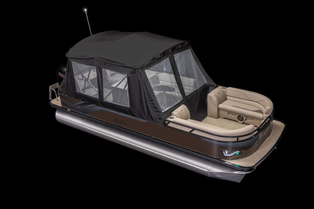 A luxury pontoon boat with a black canopy and enclosed seating area. The boat features cushioned beige seats, a sleek black and brown exterior, and is equipped with green navigation lights at the front. The background is completely black.