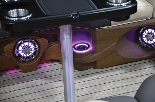 Close-up view of the interior of a luxury boat, showing modern LED-lit speakers, cupholders, and stylish wood paneling. The floor features a striped pattern. The image provides a glimpse of the premium materials and attention to detail in the boat's design.