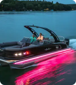 Avalon pontoon traveling on a lake at high speed, with pink side lights and custom captains chair.