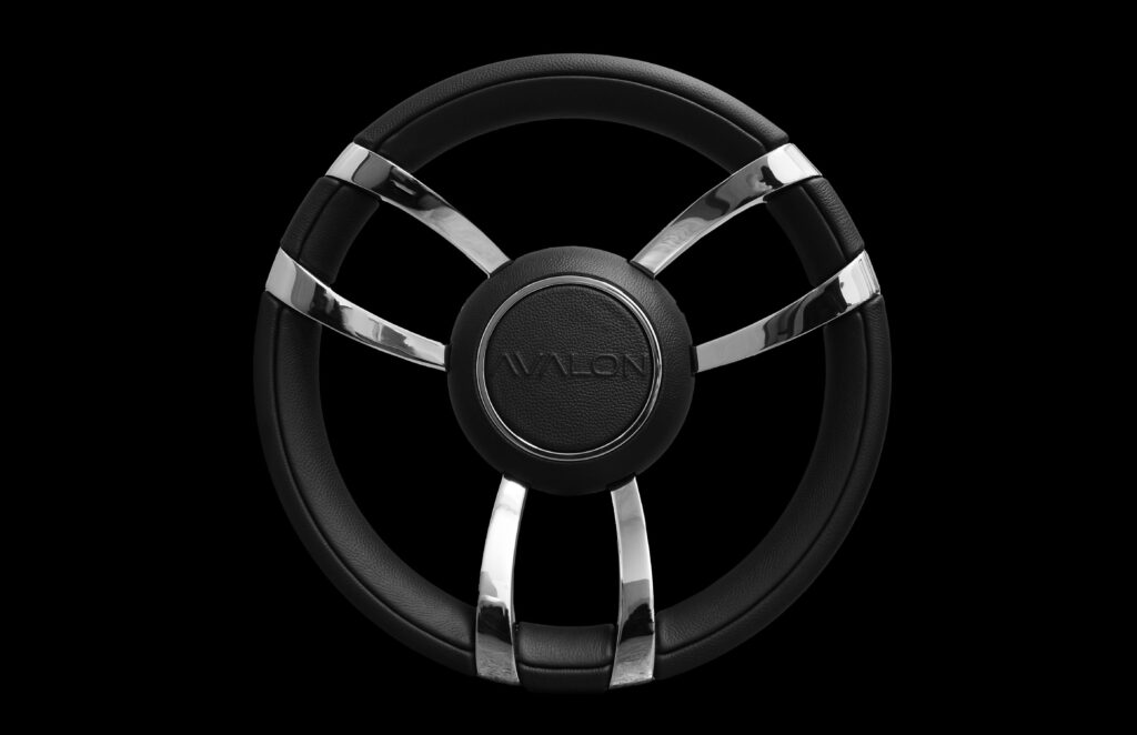 A black steering wheel with four metallic chrome spokes and the word "AVALON" embossed in the center, displayed on a plain black background.