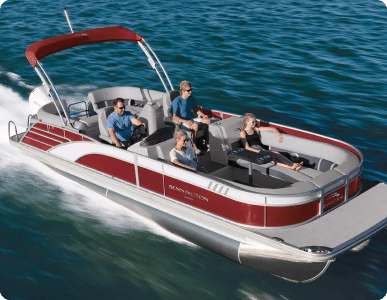 A group of four people enjoying a ride on a red and silver luxury pontoon boat gliding through blue waters. The boat features a shaded canopy and comfortable seating. The passengers are sitting relaxed, with one steering the boat.