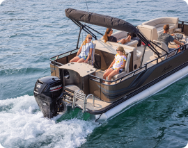 A family relaxes on a motorized pontoon boat cruising on a calm body of water. The boat has a canopy providing shade and seating for the passengers, including adults and children. The blue water gently ripples as the boat moves forward. It's easy to find similar pontoons near me for a perfect outing.