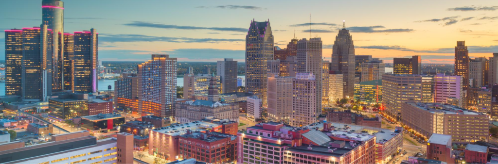 A panoramic view of the Detroit skyline at sunset, featuring a mix of modern glass high-rises and historic buildings under a sky transitioning from daytime blue to evening hues. The city's iconic Renaissance Center is illuminated on the left, with a serene river below where a pontoon boat for sale drifts lazily.