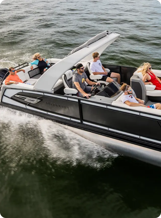 A motorboat, comparable to the cost of a pontoon boat, speeds across the water with six people on board. Two individuals are at the helm, navigating, while the others relax. The boat creates a wake as it moves through the water.