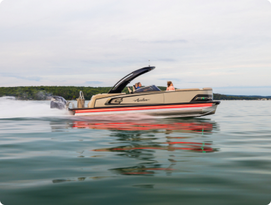 A speedboat with people onboard glides swiftly across a calm lake. The water reflects the boat and surrounding greenery. The sky is overcast, creating a serene atmosphere.